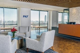 PKF Texas lobby with white couch seating area in front of the front desk and windows overlooking downtown