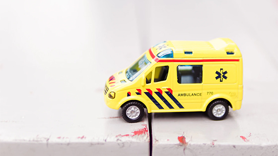 a yellow toy ambulance with red and black stripes sitting on a white wood table; image used for a blog post about tax deductions for medical expenses