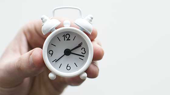 person holding a little alarm clock; image used for blog post about not-for-profit board meetings and keeping them short