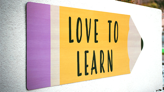 billboard painting of a pencil with a pink eraser on the left and yellow middle with black writing "love to learn," for a blog post about Coverdell Education Saving Account
