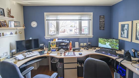 view of a desk stretching from wall to wall with two separate laptop set ups; image used for blog post about tax deductible expenses for investors or traders