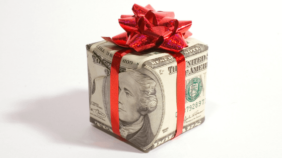 A box wrapped in money bills and tied with a bow on top; image used for blog post about educating not-for-profit donors about taxes