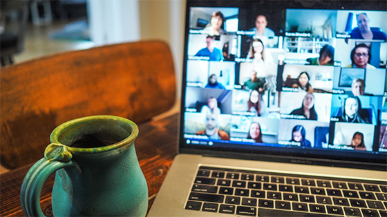 a mug and laptop with a video conference call sitting on a wooden table; image used for blog post about collaboration between development and accounting in a not-for-profit