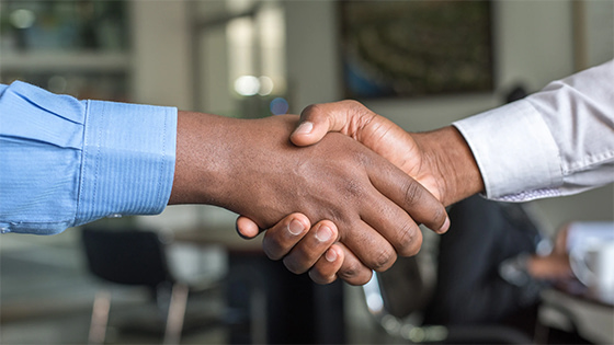 two men in suits shake hands; image used for blog post about not-for-profit merger after pandemic