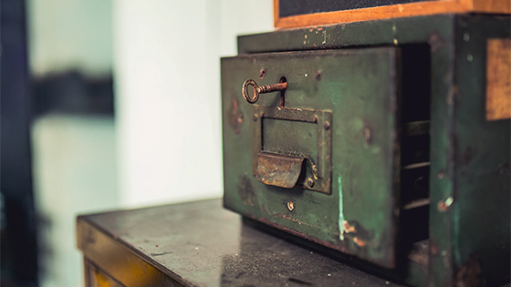 a vintage green safe sitting on a wooden table with a key in the lock; image used for blog post about not-for-profits rebuilding their operating reserve