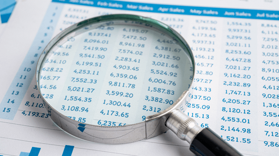 A photo of a magnifying glass sitting on top of a document with financial numbers; image used for blog post about ways not-for-profits can monitor financial health