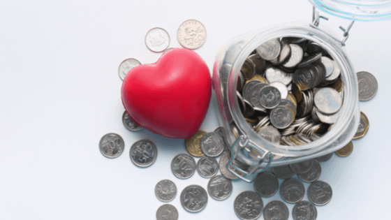 A heart stress ball sitting on top of coins next to a jar of coins; image used for blog post about charity gift appraisal