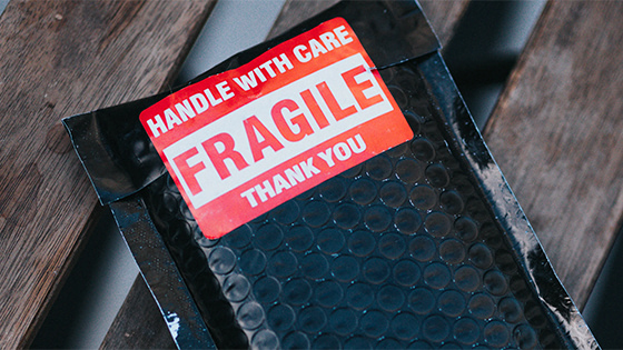 package wrapped in black bubble wrap with red label "Handle with Care. FRAGILE. Thank you."; image used for blog post about not-for-profit protecting tax-exempt status
