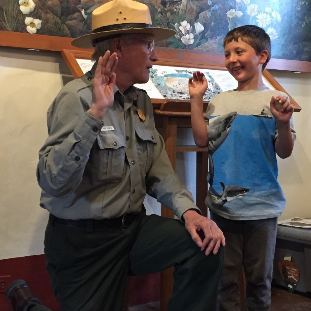 National Parks Ranger saying junior ranger pledge with a boy during a roadschool field trip