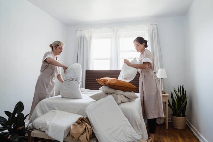 housekeepers changing bed covers and pillow cases