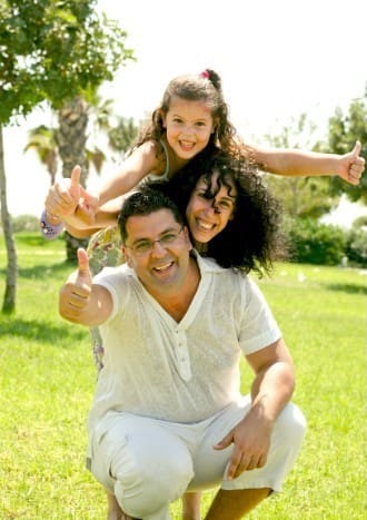 Happy family giving a thumbs-up in a well-maintained green lawn