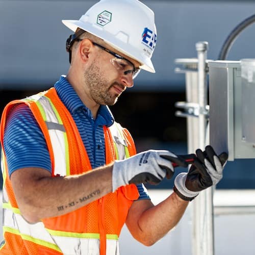 Commissioning emergency power systems technician inspecting electrical panel for backup reliability