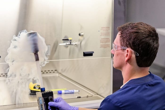 EAB Technician using smoke test to validate airflow patterns in a controlled cleanroom