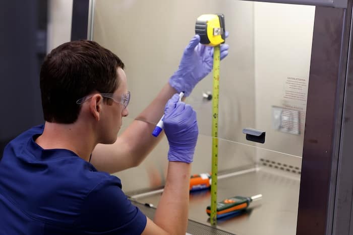 Specialist using tape measure to verify equipment setup in a controlled environment