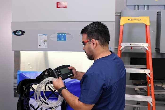 Specialist conducting HEPA filter leak test using photometer and tubing in a controlled environment