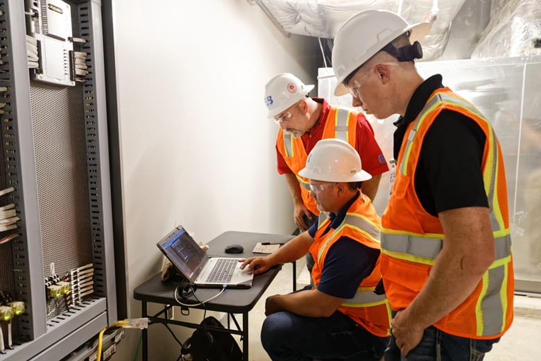 Three EAB engineers analyzing system data on a laptop