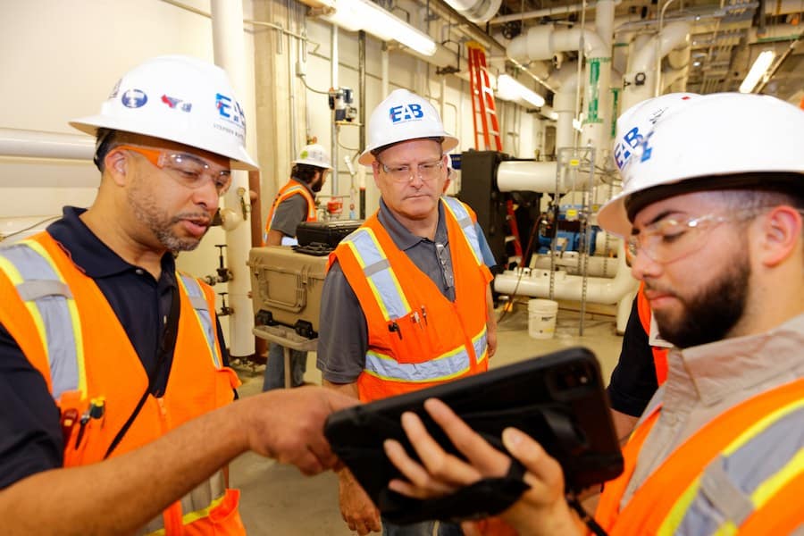 Engineered Air Balance commissioning engineers reviewing building system data on a tablet during an on-site inspection