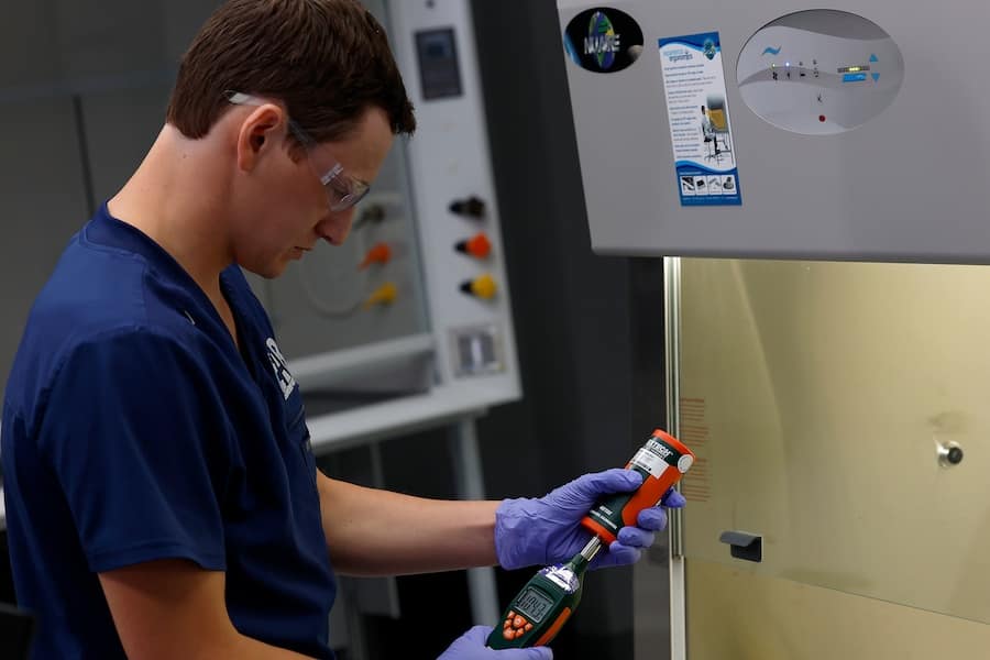Engineer performing cleanroom testing with airflow measurement device in a controlled environment