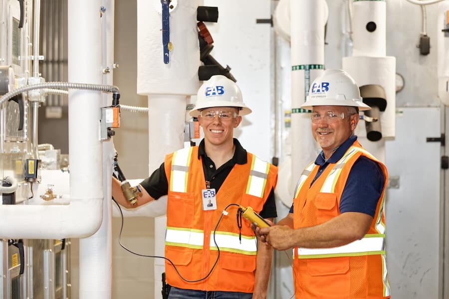 Professional EAB air balancing engineers using diagnostic tools to optimize HVAC systems