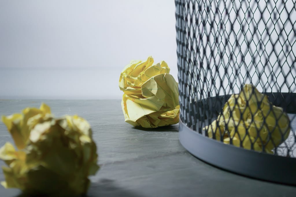 Camping trash can surrounded by paper