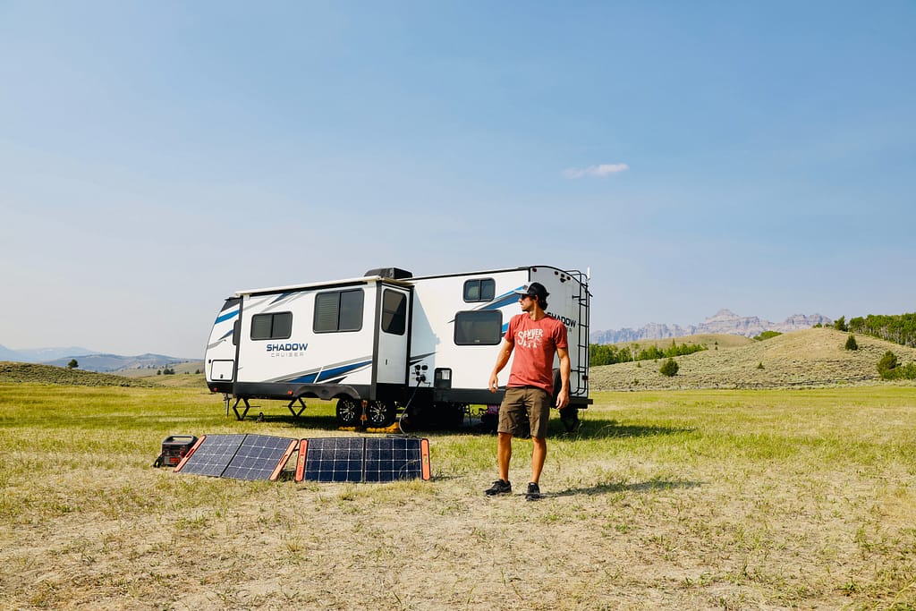 Solar panels in front of a trailer in a field, the perfect answer to how to charge RV batteries