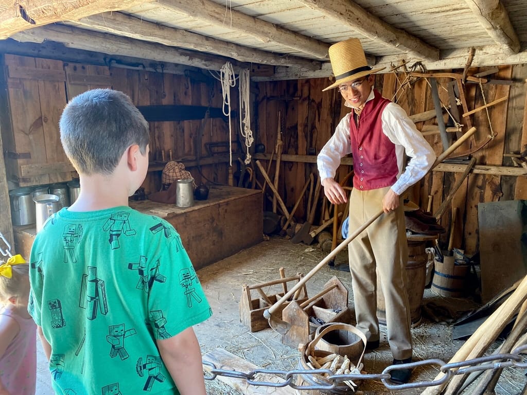 Boy talking to interpreter about farm life at Old Sturbridge Village living history museum