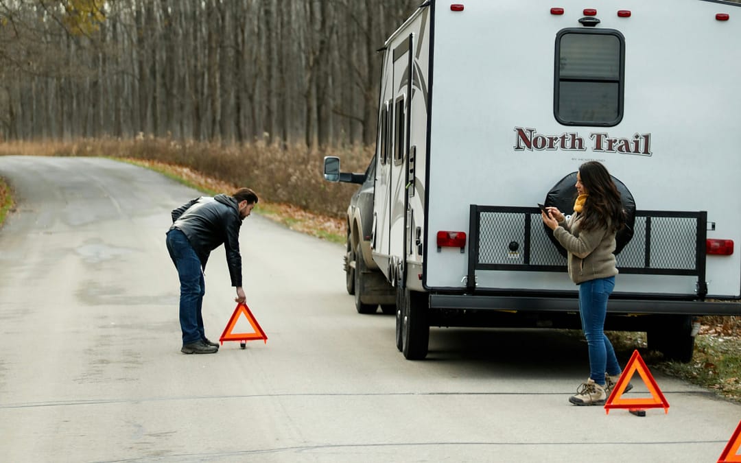 Couple next to trailer calling RV roadside assistance
