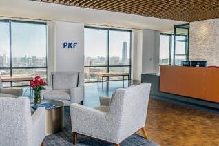 PKF Texas lobby with white couch seating area in front of the front desk and windows overlooking downtown