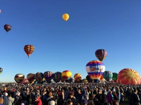 Balloons take flight as a crowd cheers