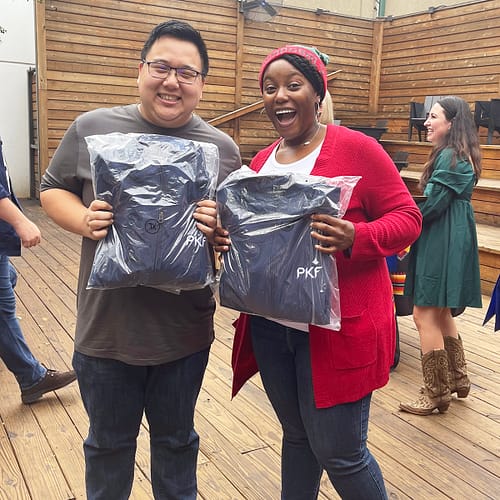 Photo of PKF Texas team members holding packaged jackets at a firm event