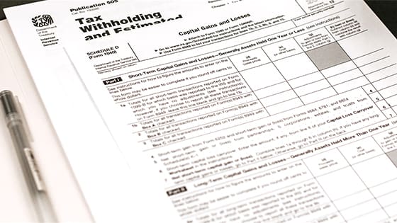 a black-ink pen lying next to tax withholding forms for a tax return