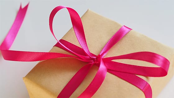a gift wrapped in brown paper tied with a pink bow to signify a gift acceptance policy for not-for-profit organizations