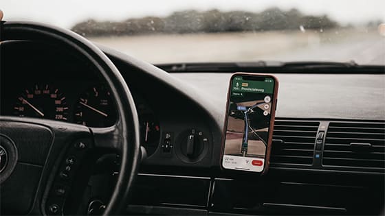 view of a car steering wheel and dashboard with a phone showing directions on a map; image used for blog about tax obligations for a side gig