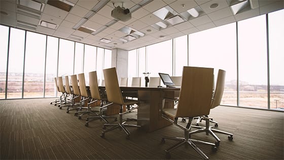 oval brown wooden conference table with chairs on wheels surrounding in a conference room with windows; image used for a blog about not-for-profit succession plan