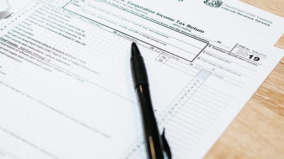 black pen sitting on top of a 2019 tax return form; image used for a blog post about IRA deductible contributions