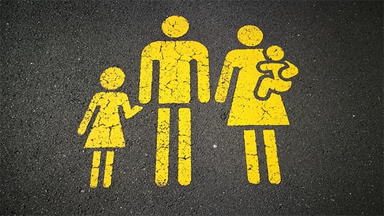 a yellow painting on the street concrete of figures in shape of a family, dad holding hands with child and mom holding baby; image used for blog post about keeping life insurance policy out of estate