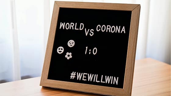 a blackboard with white letters spelling "world vs. corona; 1:0; #WeWillWin," image used for a blog post about not-for-profits partnering up during COVID-19 pandemic