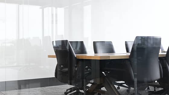 six black leather chairs sit around a wooden table in a conference room; image used for a blog post about rebuilding a not-for-profit board