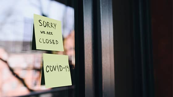 two sticky notes on a window saying "Sorry we are closed, COVID-19;" image used for blog post about tax consequences of PPP loans