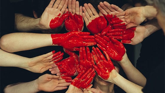 hands coming together with a red heart painted on them; image used for blog post about not-for-profits collective impact initiative requirements