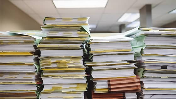 files and books of paper stacked across a shelf; image used for blog post about keeping tax records or throwing them away