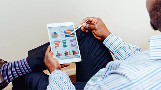 man in a suit looking at graphs and stats on a tablet; image used for blog post about not-for-profits minimizing financial adjustments