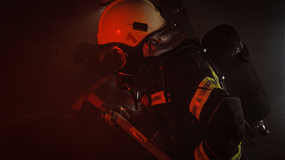 a fire fighter carrying an axe in the dark; image used for blog post about not-for-profits having a plan to limit disaster damage