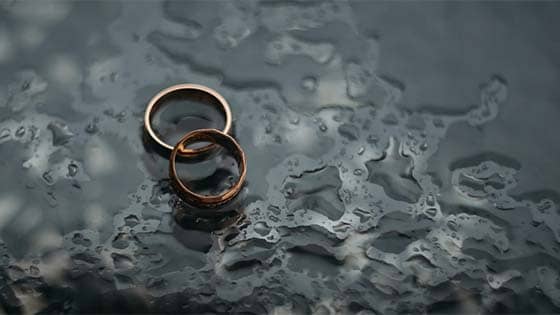 two rings sitting on the ground surrounded by rain drops; image used for blog post about tax implications for business owners going through divorce