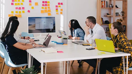 five people sitting at a table looking at a computer screen; image used for blog post about not-for-profits considering sponsoring a charitable project