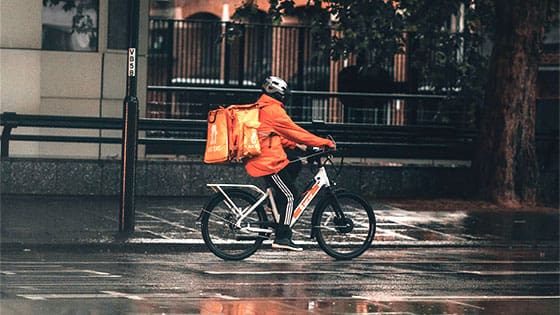 a person riding a bicycle carrying a food delivery on their back; image used for blog post about gig workers and their tax obligations