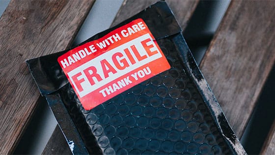 a mailing package with a sticker reading, "Handle with Care - Fragile - Thank you;" image used for blog post about not-for-profits handling restricted gifts with care