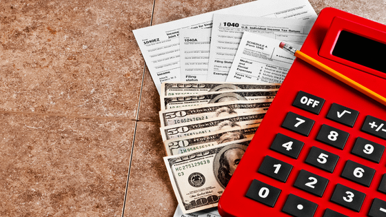 A photo of a tax 1040 form, cash, and a calculator; image used for blog post about estimated tax payments