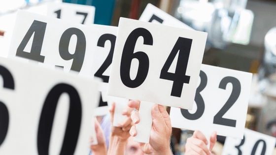 An image of people holding up auction boards with numbers