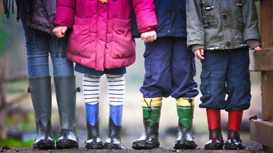 A photo of four children dressed in rain gear to show how families can be affected by the new kiddie tax laws.